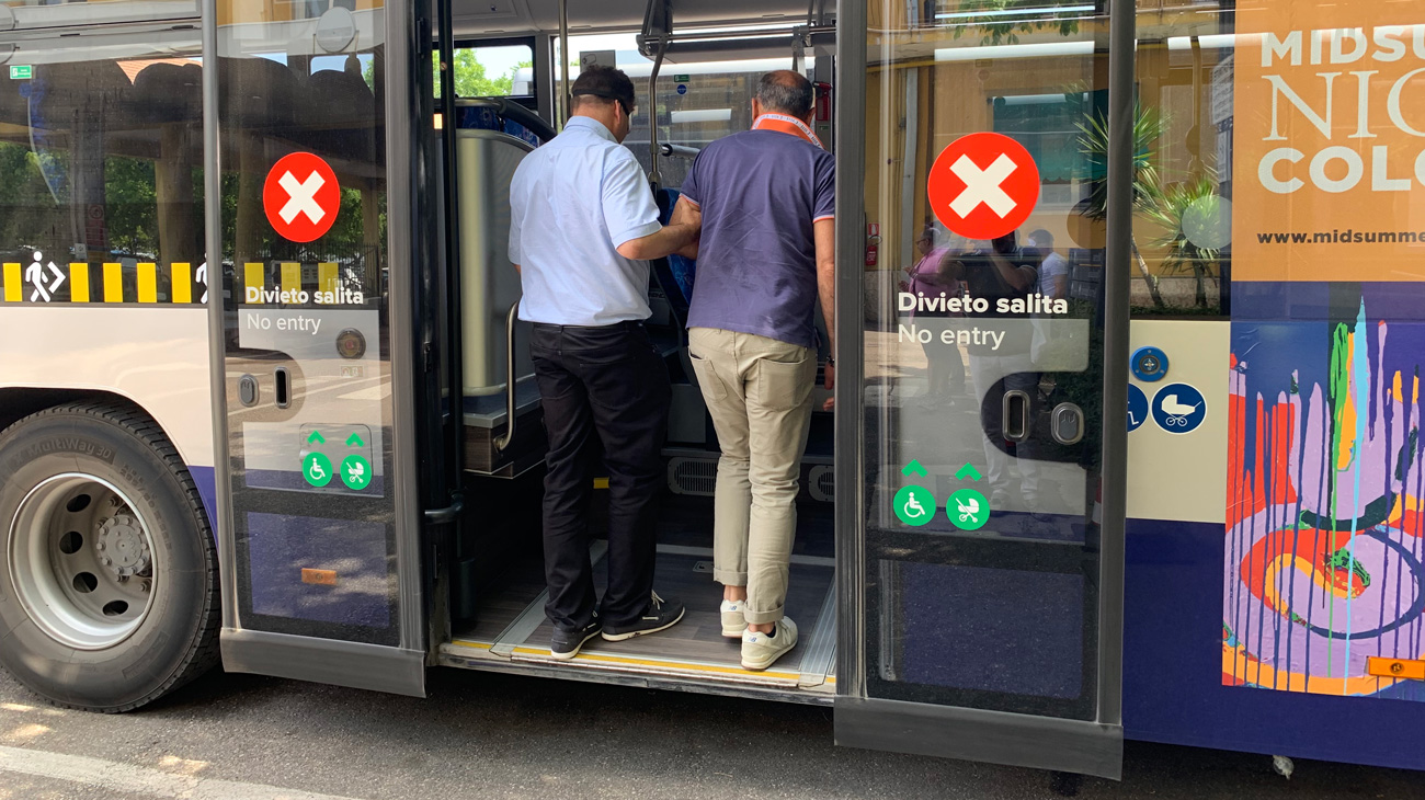 Un autista atv accompagna un suo collega bendato per simulare la salita sull'autobus