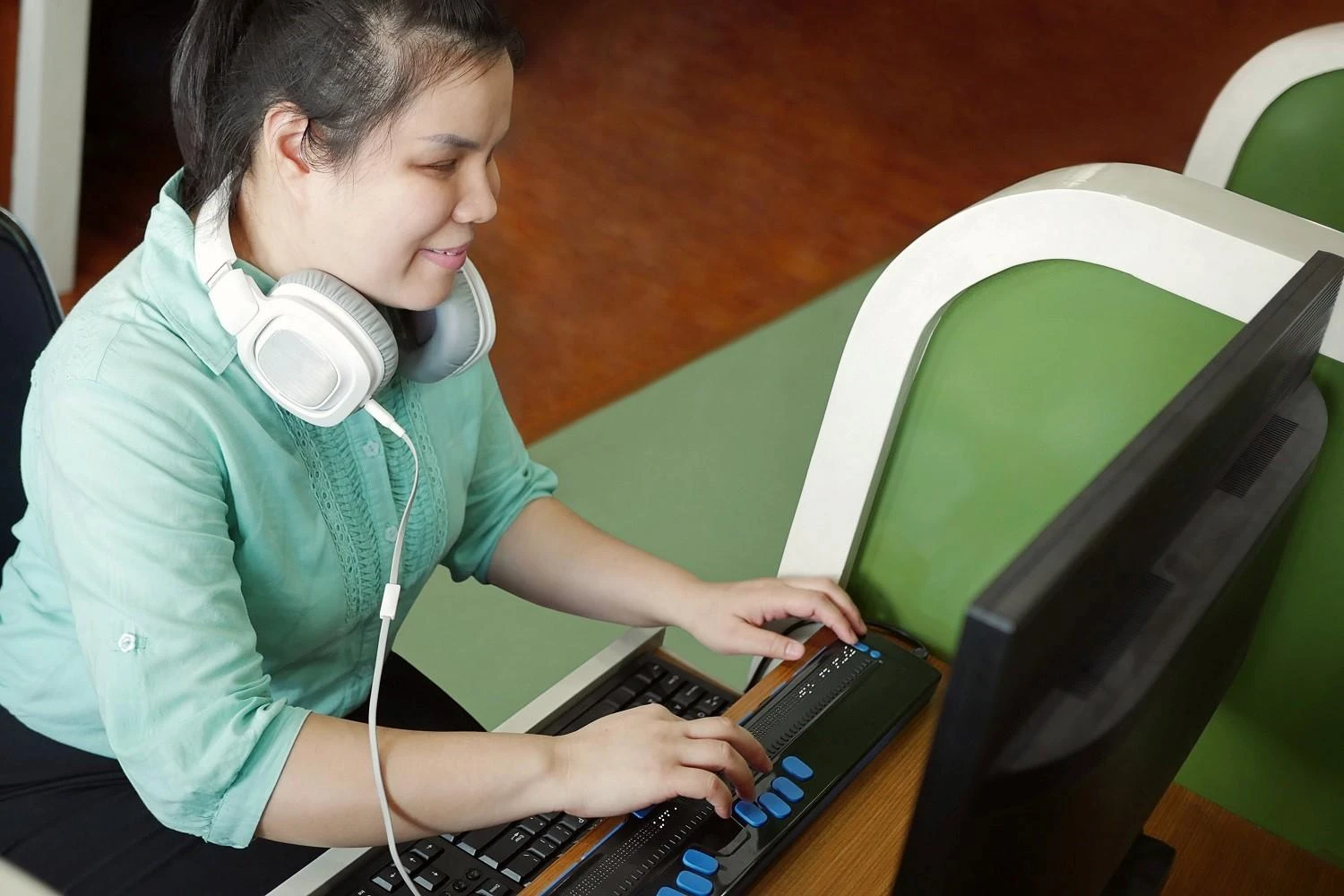 Una persona davanti a un computer mentre utilizza uno screen reader e la tastiera braille per accedere ai contenuti di una pagina web.